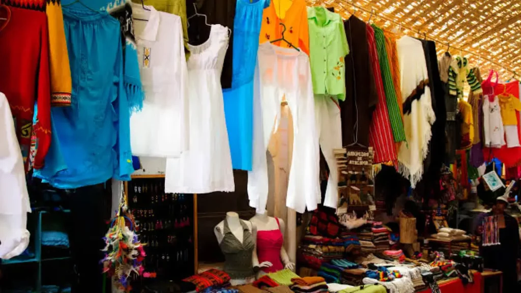 Roupas tradicionais e artesanatos pendurados em uma barraca de mercado em San Pedro de Atacama, exibindo uma variedade de cores e estilos típicos da região.