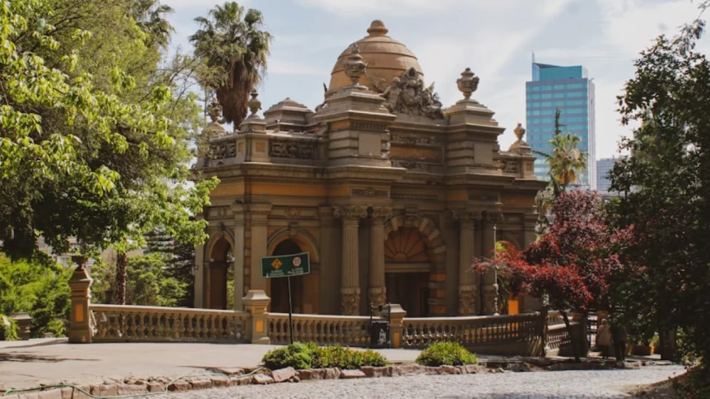 Detalhe da arquitetura do Castelo Hidalgo no Cerro Santa Lucía, em Santiago, rodeado por vegetação e com um fundo urbano.