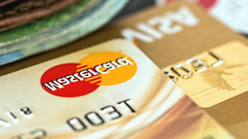 Cartões de crédito e débito sobre uma mesa, com destaque para o logo da Mastercard em um deles."