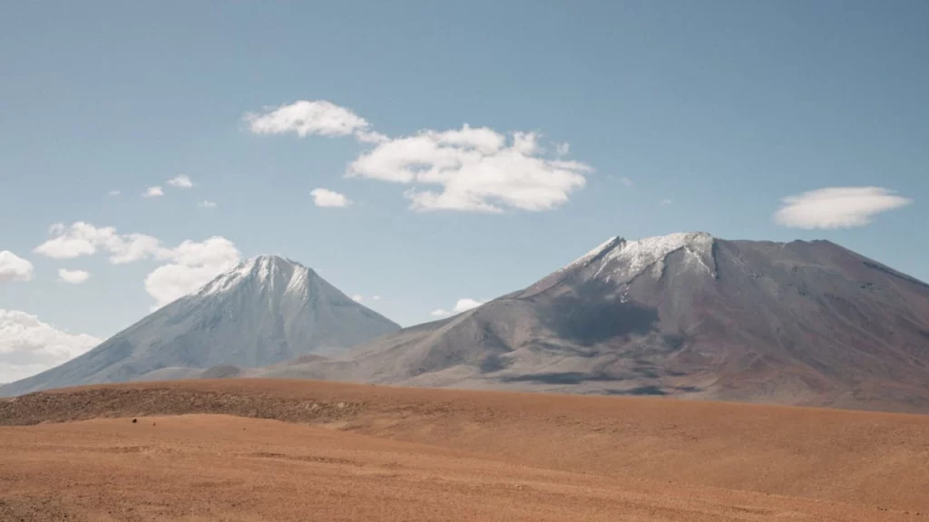 Vulcões cobertos de neve no horizonte do Deserto do Atacama, uma das vistas icônicas que tornam essa região única no mundo.