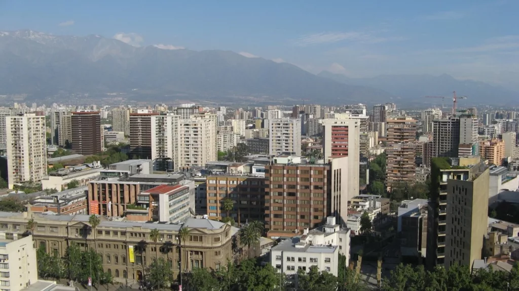 Vista panorâmica da cidade de Santiago, Chile, com edifícios modernos em contraste com as majestosas montanhas dos Andes ao fundo, uma combinação de urbanismo e natureza.